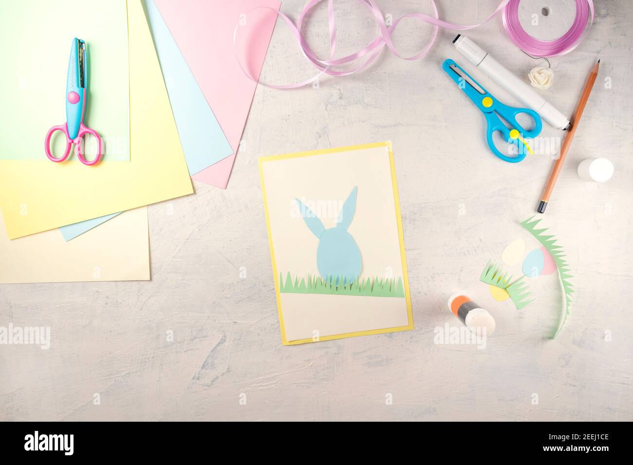 Istruzioni passo per passo: Come fare la carta Buona Pasqua. Creatività fai da te. Punto 4 colla il coniglio di carta, l'erba e le orecchie di coniglio. Artigianato pasquale fatto a mano. Vista dall'alto Foto Stock