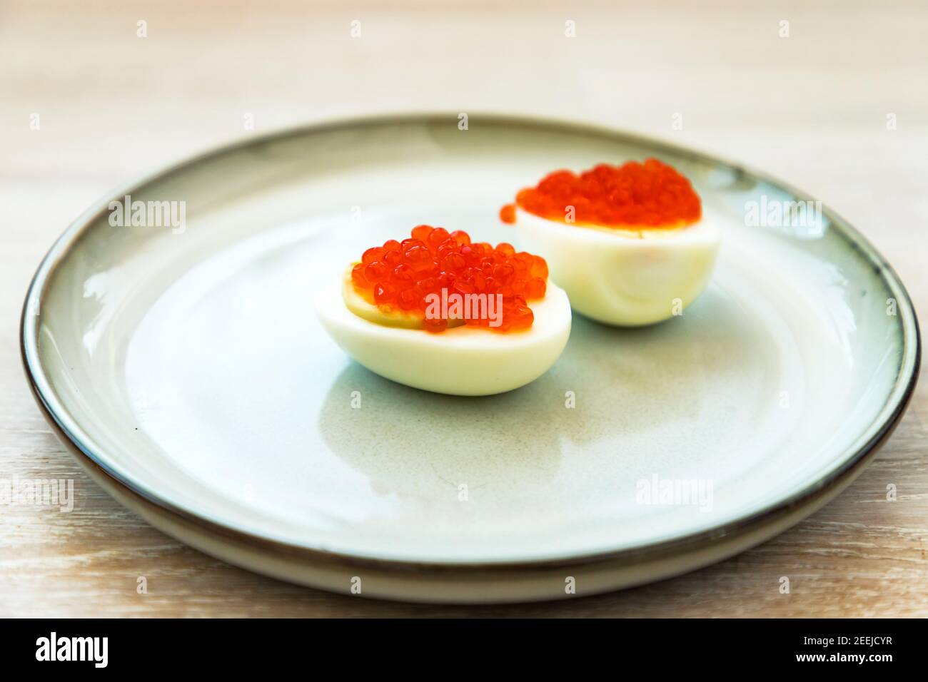 Caviale rosso farcito uova a metà, tipico spuntino russo primo piano della piastra grigio blu Foto Stock