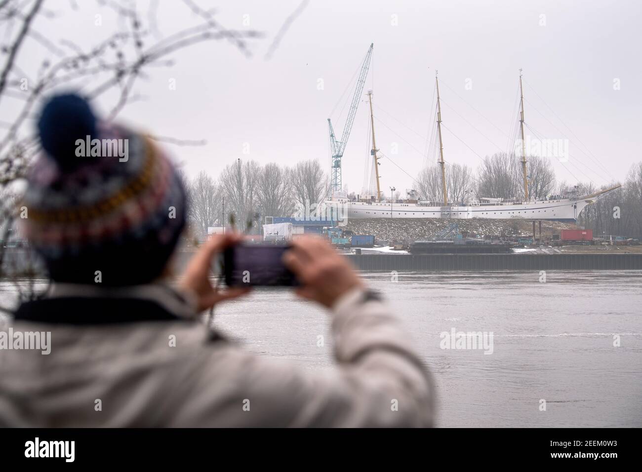 Berna, Germania. 16 Feb 2021. Una donna scatta una foto della nave da addestramento 'Gorch Fock' presso il cantiere navale di Lürssen. Il costoso e lungo rinnovo della nave di addestramento navale sta per finire. Credit: Sina Schuldt/dpa/Alamy Live News Foto Stock
