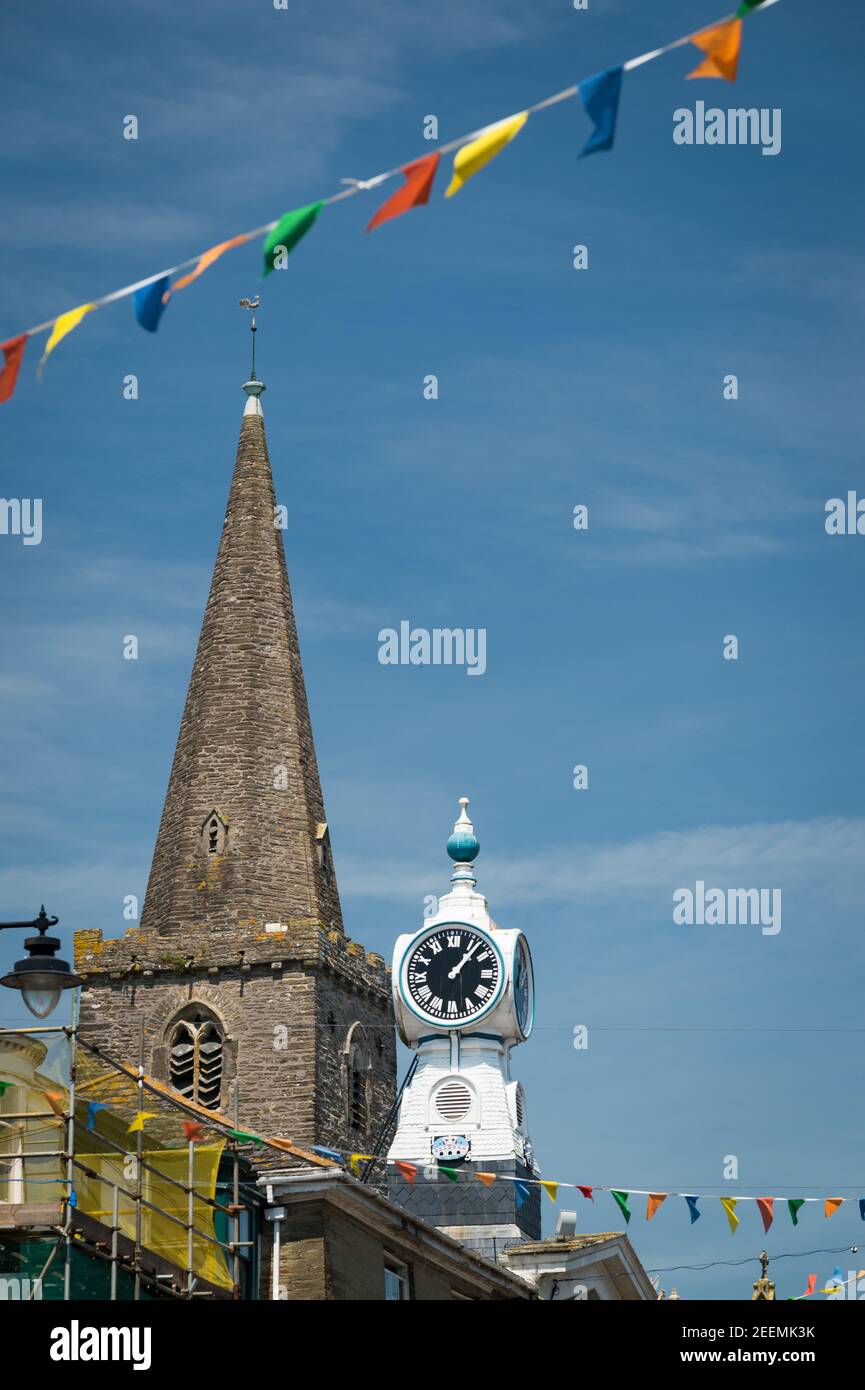 La guglia della chiesa di St Thomas Dodbrooke e St Edmund, e l'orologio sul Kings Cinema, Fore Street, Kingsbridge, Devon, Regno Unito. Foto Stock