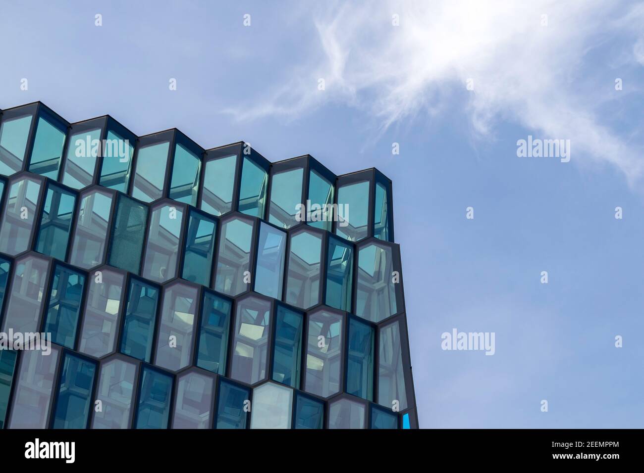 Vista diurna delle finestre angolari della Sala Concerti di Reykjavik, Harpa, vista dal basso contro un cielo blu con nuvole luccicanti, con spazio per le copie Foto Stock