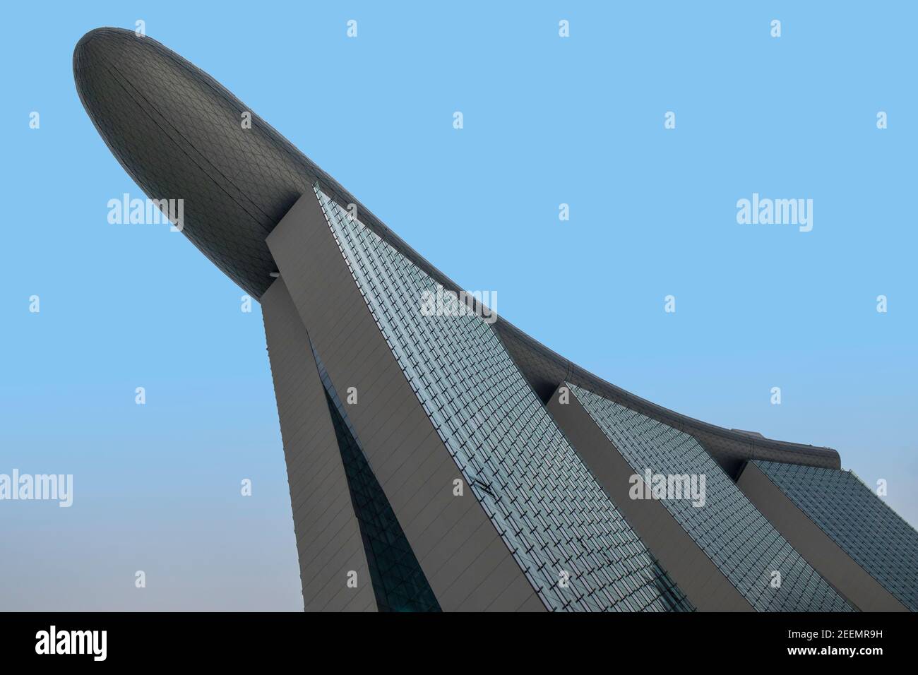 Il Marina Bay Sands Hotel, Singapore, dal basso, mostra la forma di barca proiettante del ponte più alto contro un cielo blu chiaro, con spazio di copia Foto Stock