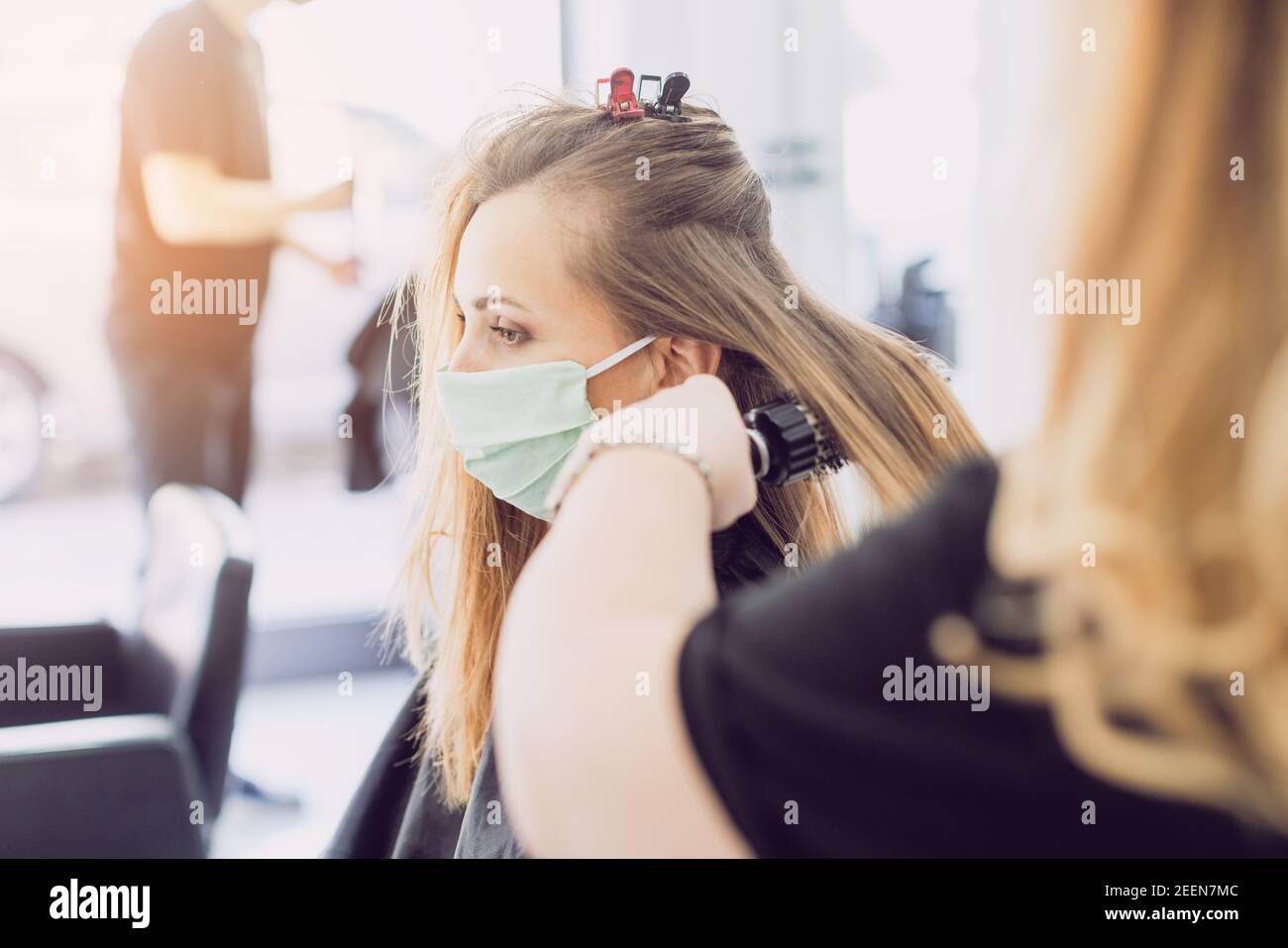 Donna che visita il parrucchiere indossando maschera Foto Stock