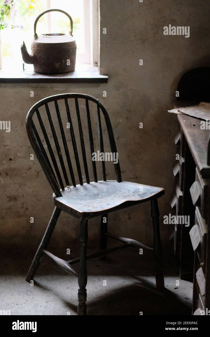 Una vecchia sedia di legno vicino alla finestra di una camera rustica ai Giardini perduti di Heligan. Foto Stock