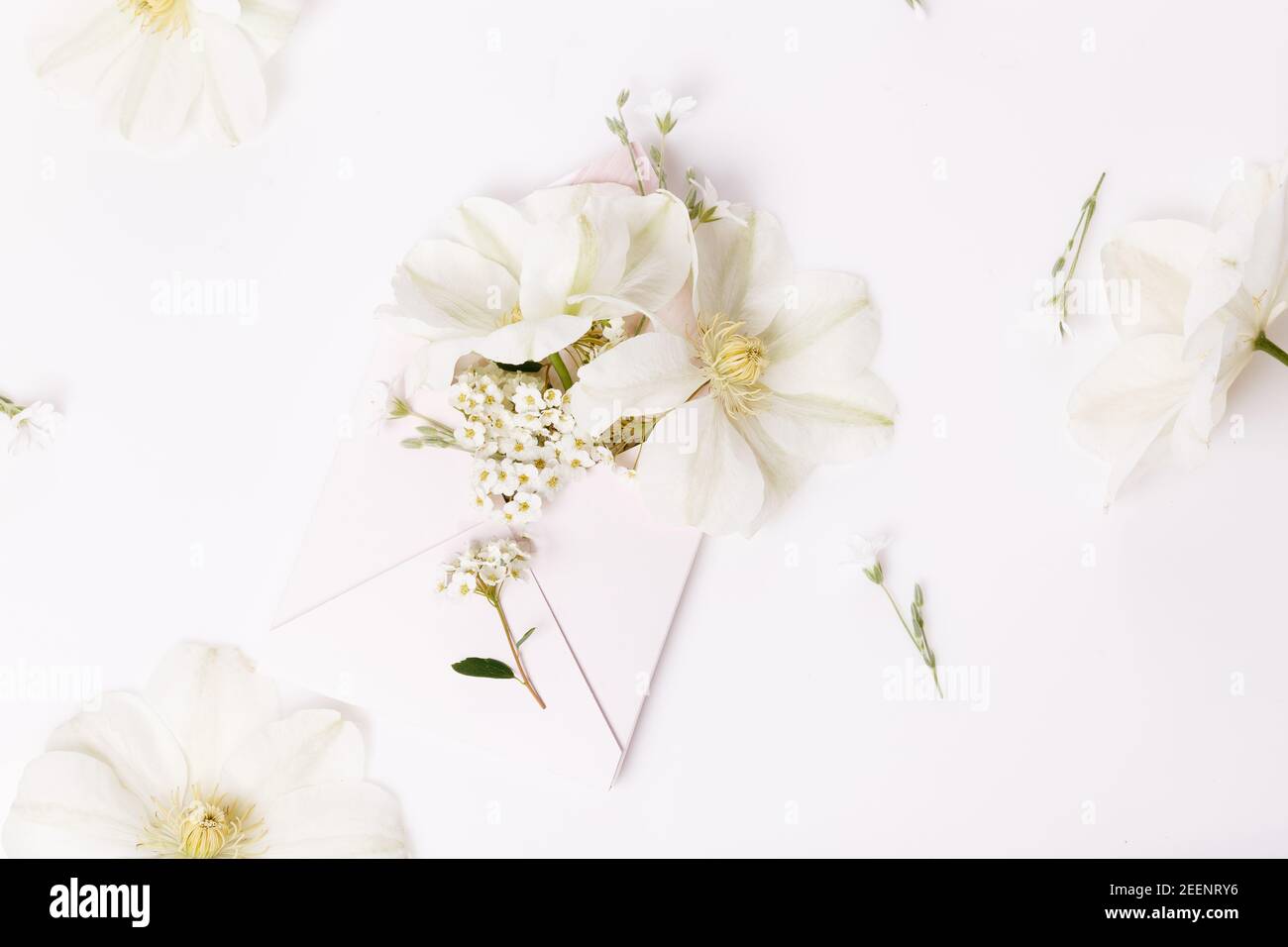 Romantico bouquet di fiori di clematis bianchi in una busta rosa, vista ravvicinata. Sfondo romantico Foto Stock