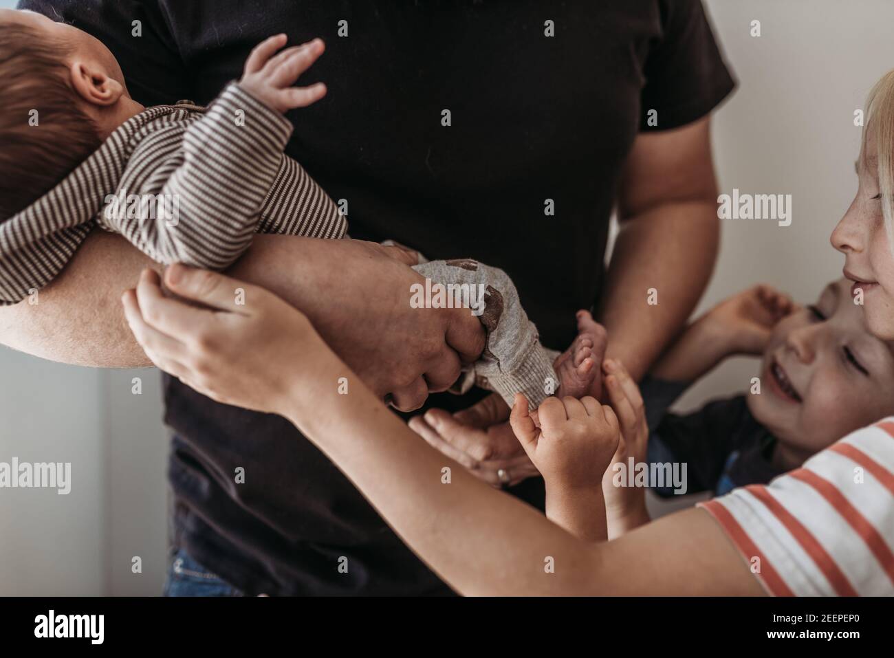 Primo piano dei fratelli che toccano il fratello neonato in ospedale Foto Stock