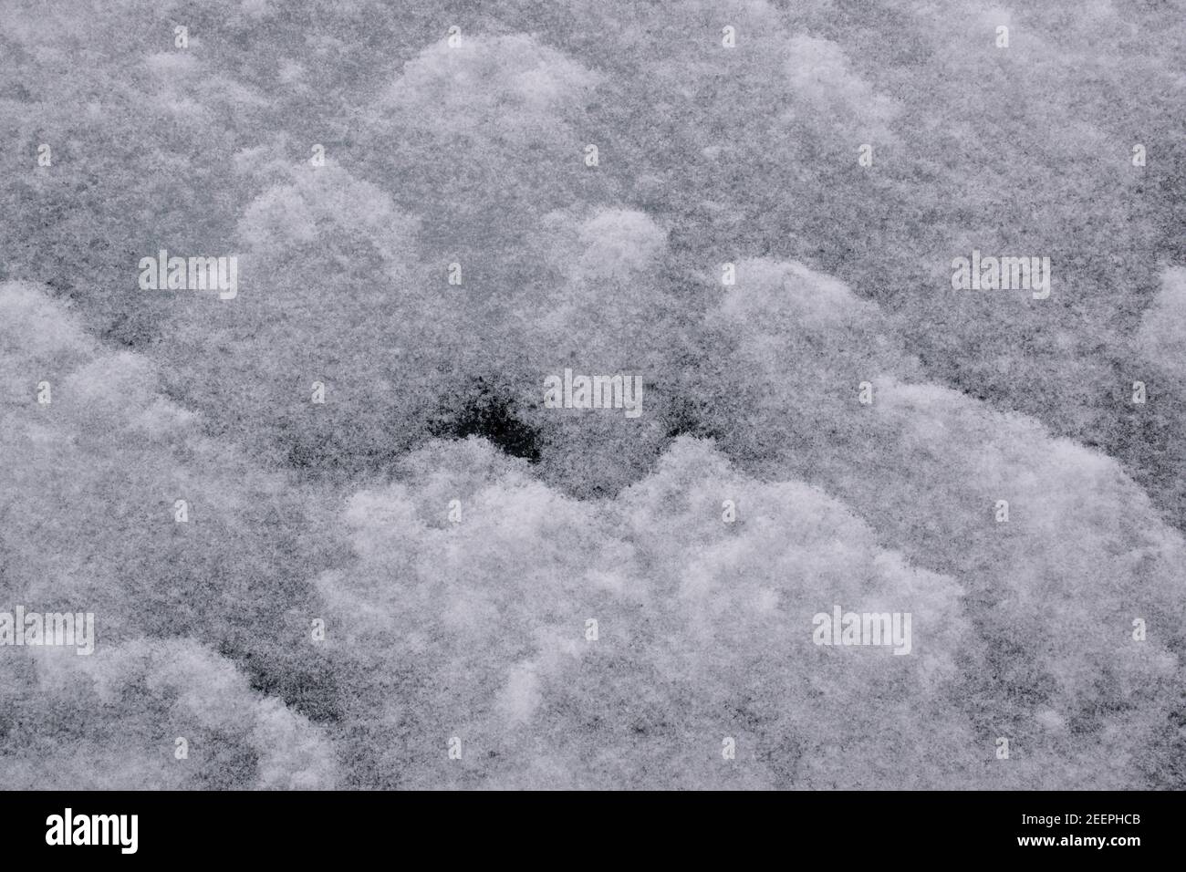 Closeup di nevicate su una finestra di auto la mattina dopo - una morbida, secca nevicata che crea forme di sovrapposizione tipo onda. Foto Stock