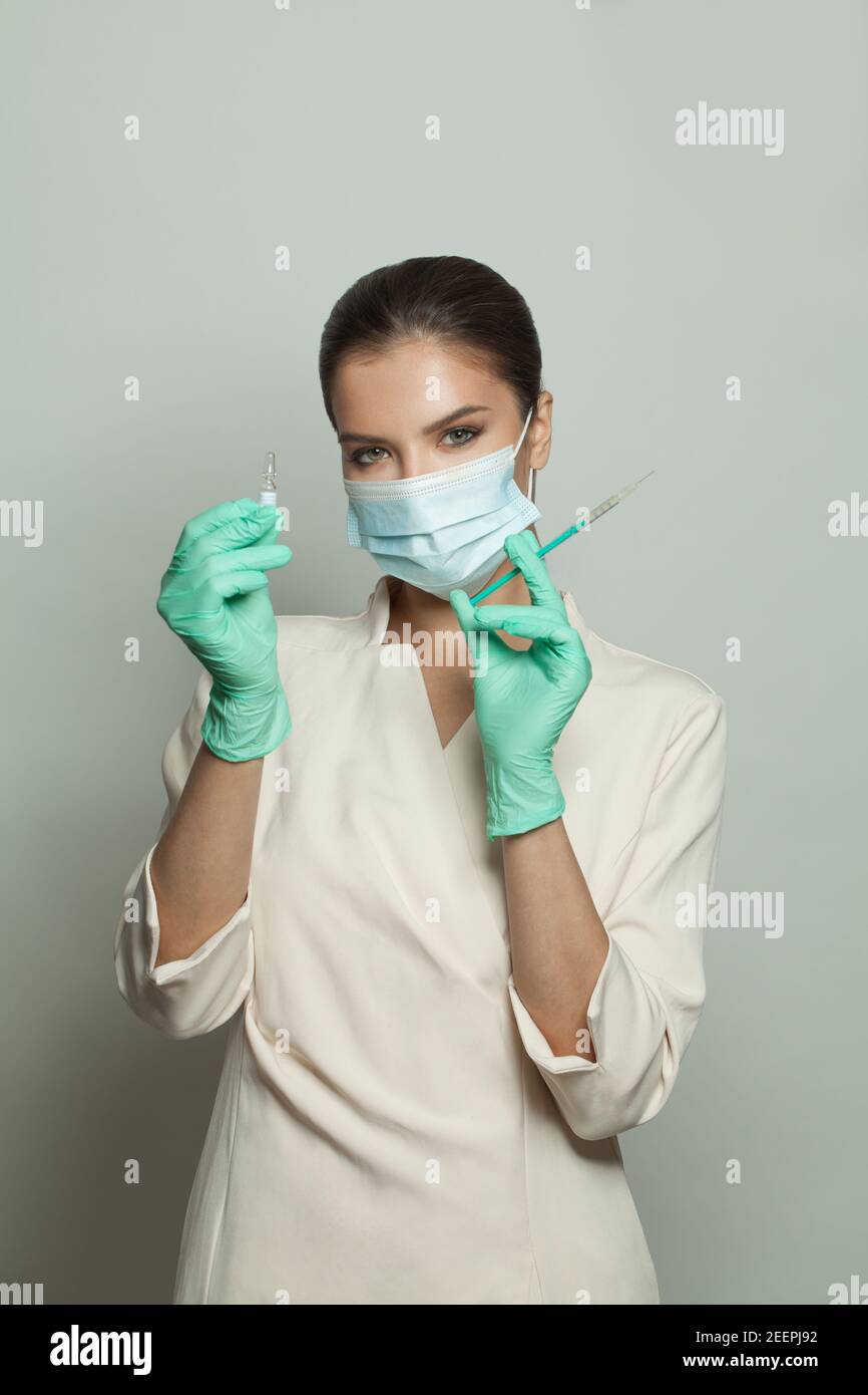 Infermiere o medico con siringa che mostra una fiala pronta per l'iniezione su sfondo bianco. Medicina, cosmetologia e concetto di vaccinazione Foto Stock