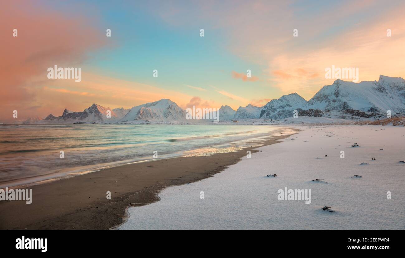 Tramonto invernale sulla costa del mare e sulle montagne, colorata alba settentrionale e luce solare nelle nuvole rosa. Isole Lofoten, Norvegia, Europa Foto Stock