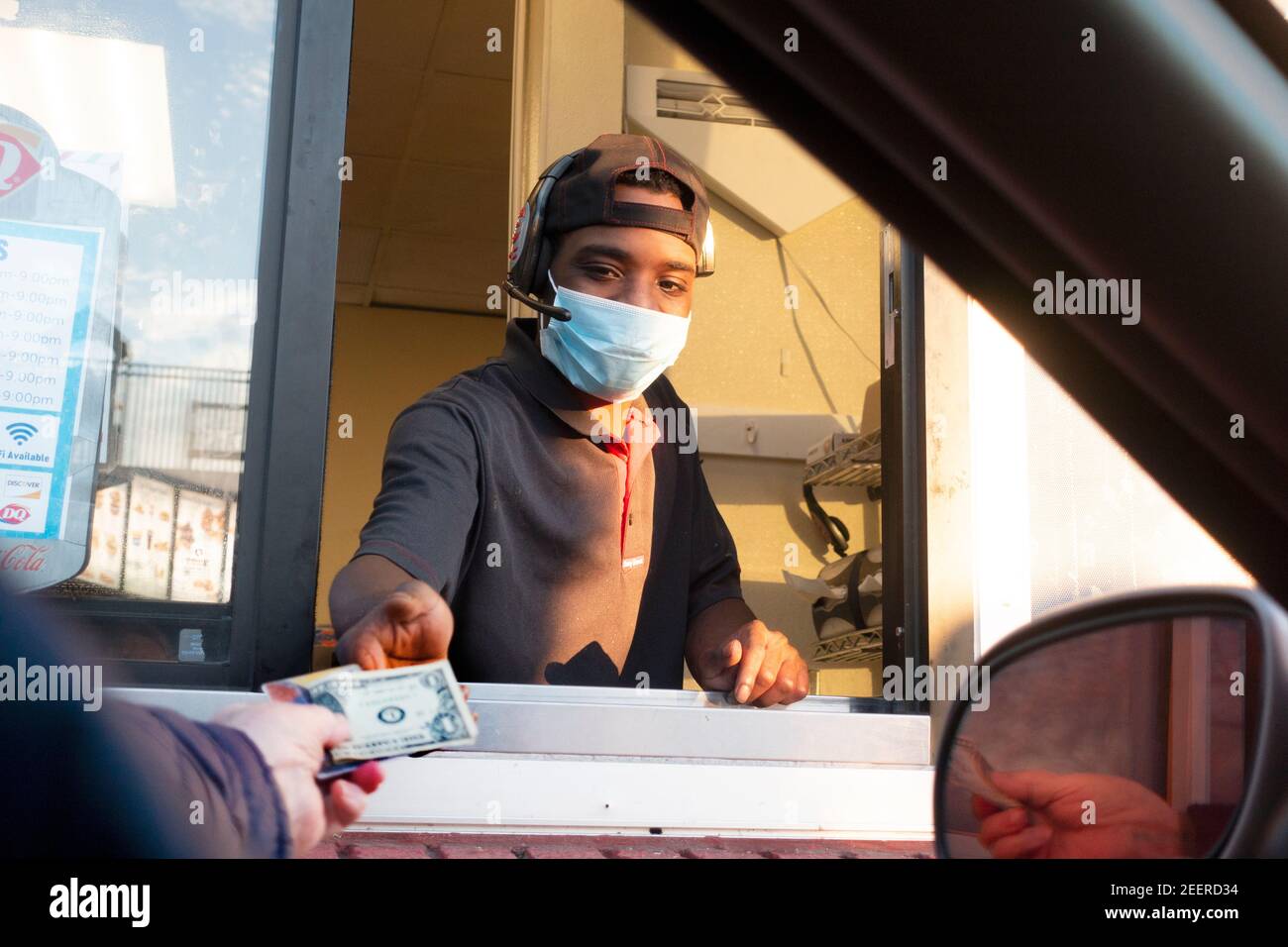 Il cliente consegna al lavoratore mascherato una mancia e una carta per pagare una Dairy Queen alla finestra di drive-up. St Paul, Minnesota, Stati Uniti Foto Stock
