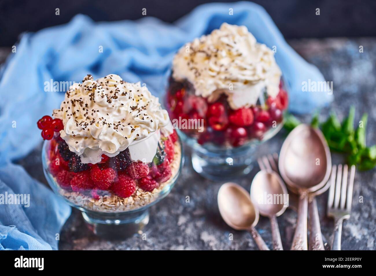 Idee di ricetta per la colazione di dieta estiva, dessert sano del mattino in vasi porzionati con frutti di bosco estivi - lampone, ciliegie, mora. Su fondo di pietra. Foto Stock