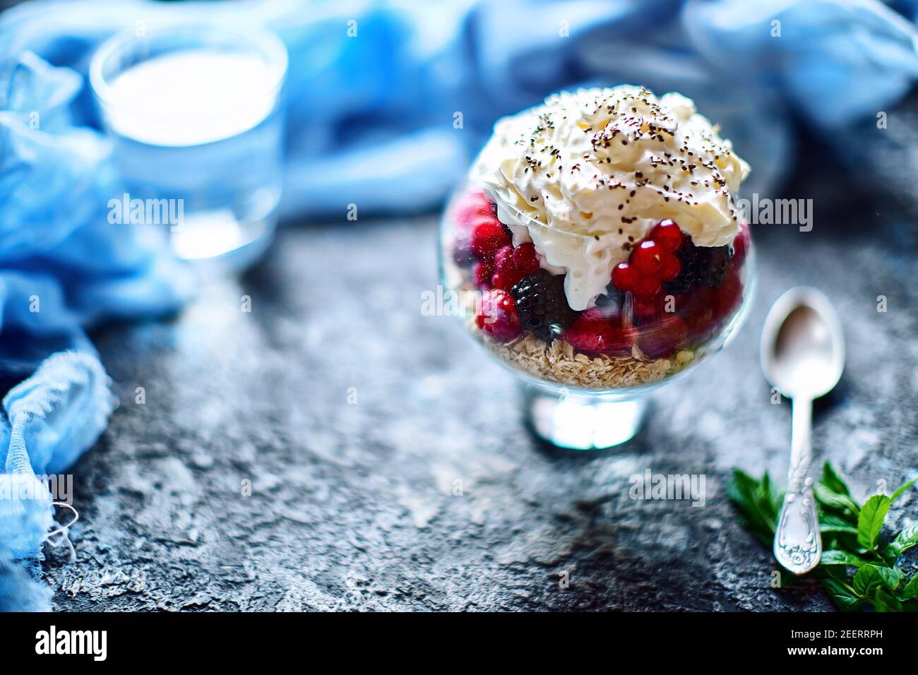 Idee di ricetta per la colazione di dieta estiva, dessert sano del mattino in vasi porzionati con frutti di bosco estivi - lampone, ciliegie, mora. Su fondo di pietra. Foto Stock