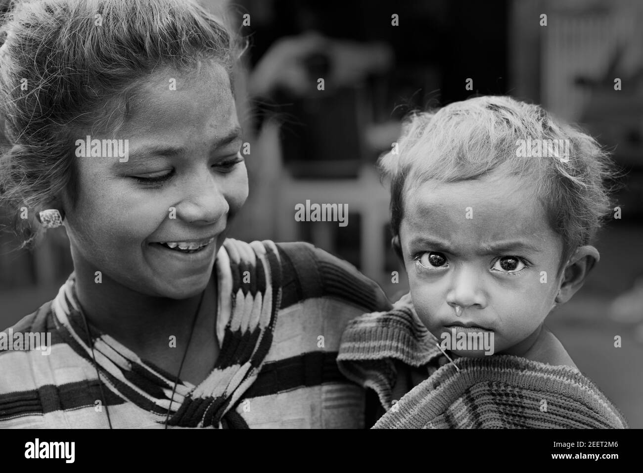 Giovane donna che tiene il bambino piangente con naso che cola e che vive sulle strade a Udaipur, Rajasthan, India. Foto Stock
