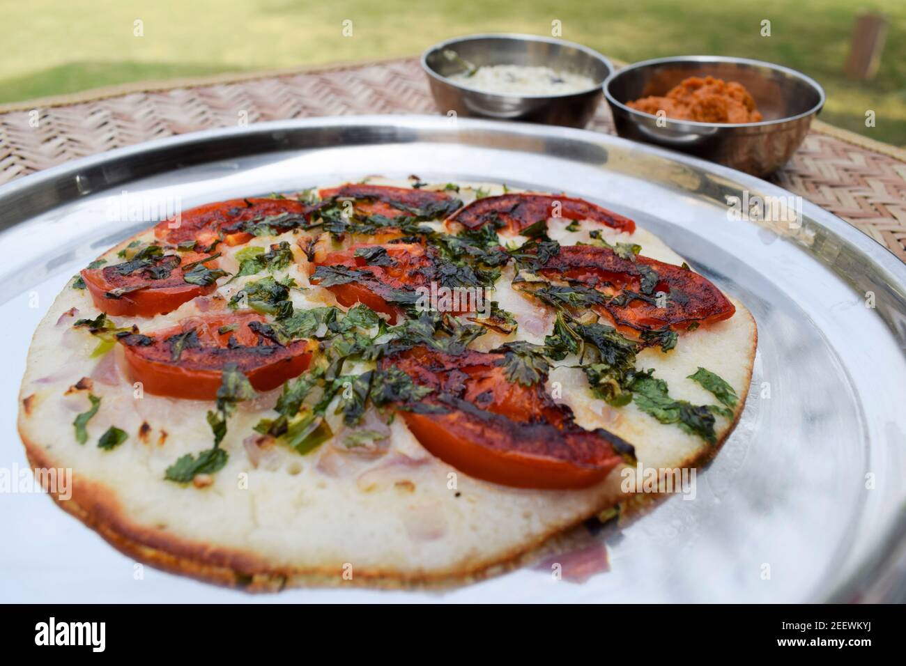 L'Uttapam, conosciuto anche come Uttapa, è un pancake indiano saporito. Condimento di pomodoro, coriandolo e cipolla a fette. Questo è l'uttapam di pomodoro Foto Stock