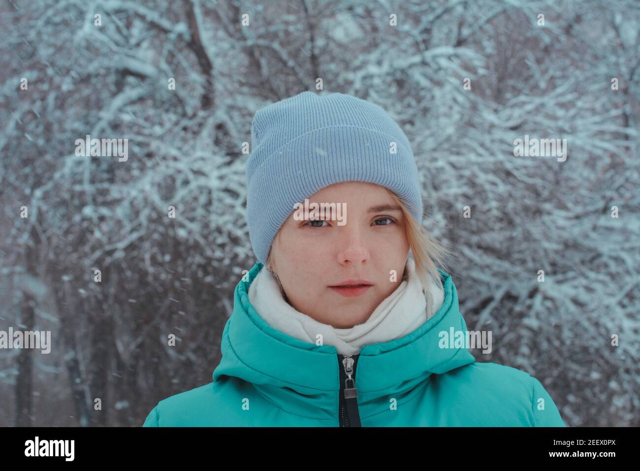 Ritratto di una bella ragazza adolescente 15 anni con occhi marroni. Sfondo di rami di alberi in brina e nevicata. Foto Stock