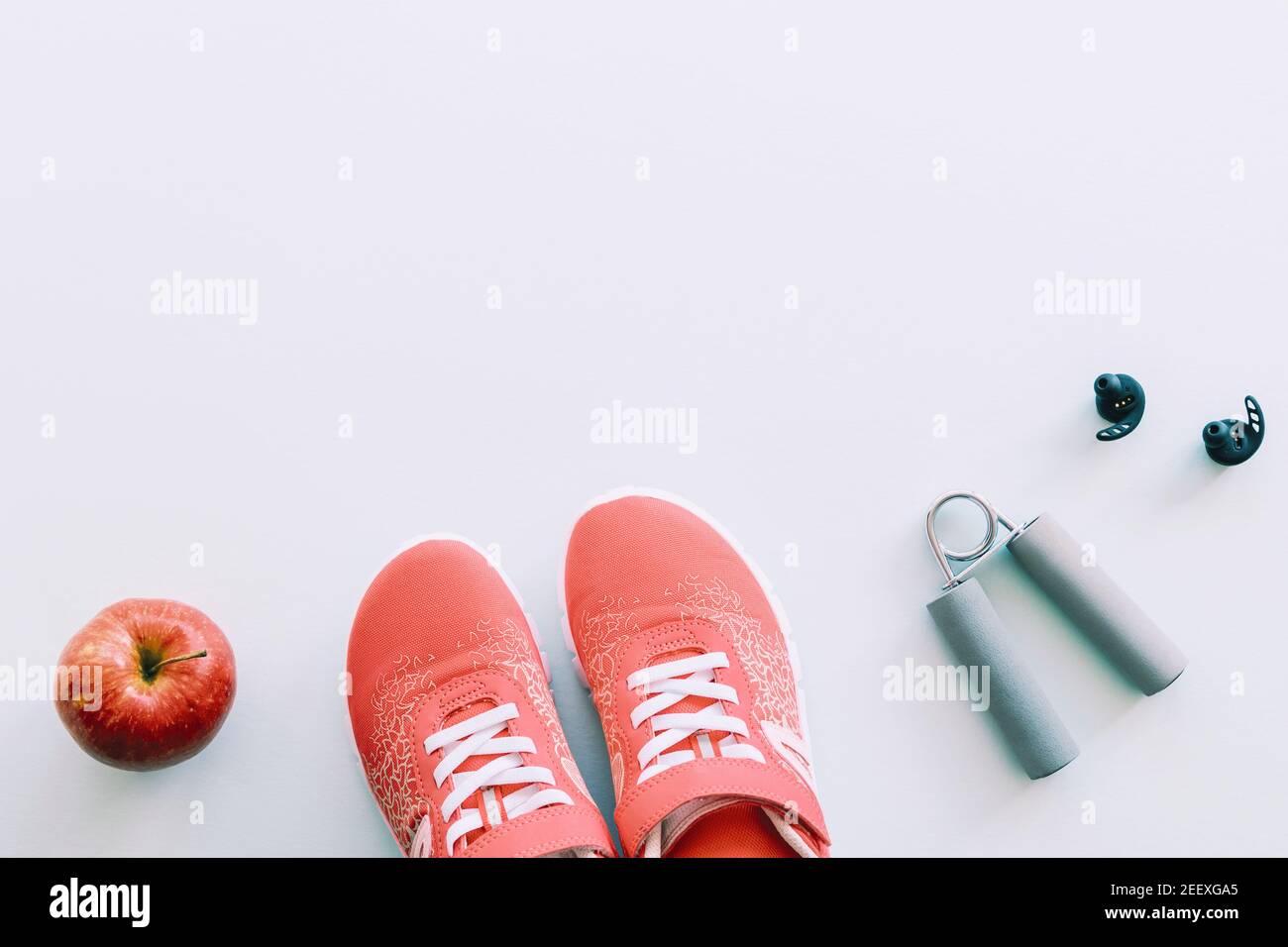 Sneaker rosse, attrezzi sportivi e scarpe da ginnastica, mela su sfondo blu. Concetto di vita sana e di formazione, vista dall'alto, piano di posa, spazio di copia. Foto Stock