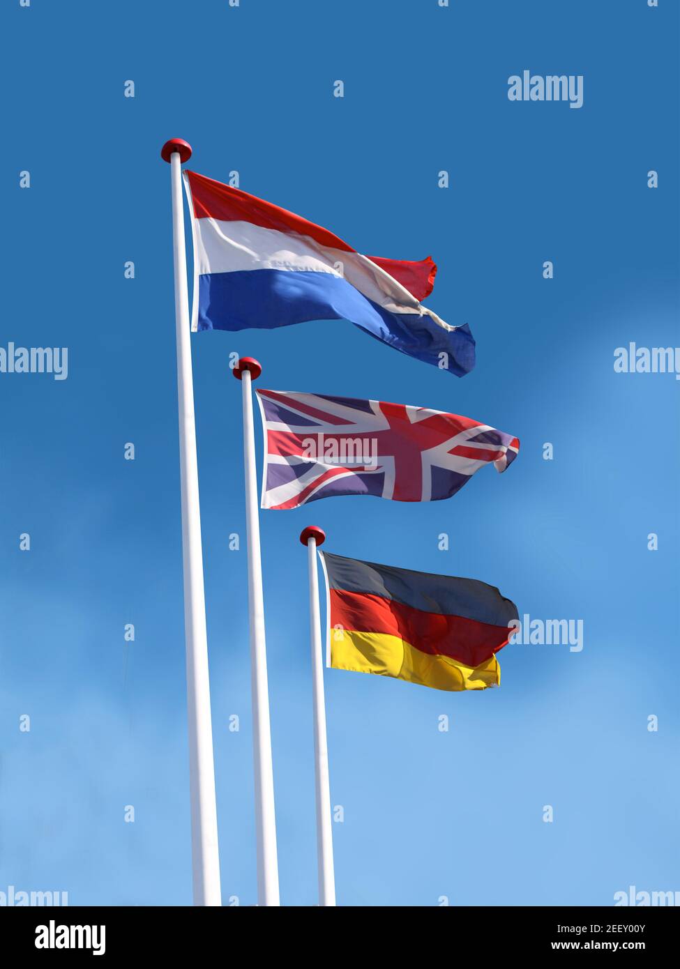 Bandiere di Francia, Regno Unito, Germania su pali di bandiera. Bandiera della Francia è in cima. Sfondo blu cielo. Foto Stock