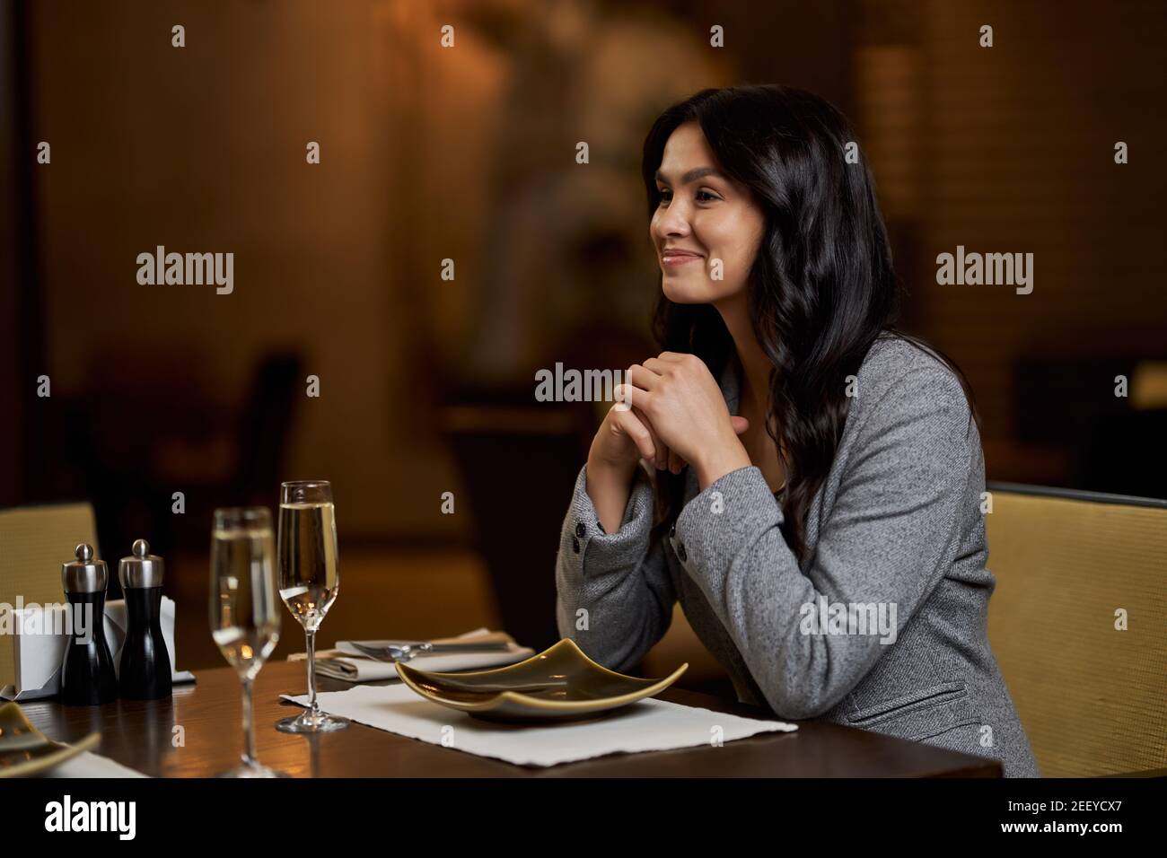 Copia-spazio foto di bella donna bruna sorridente e seduta a. il tavolo del ristorante con il piatto davanti a lei Foto Stock