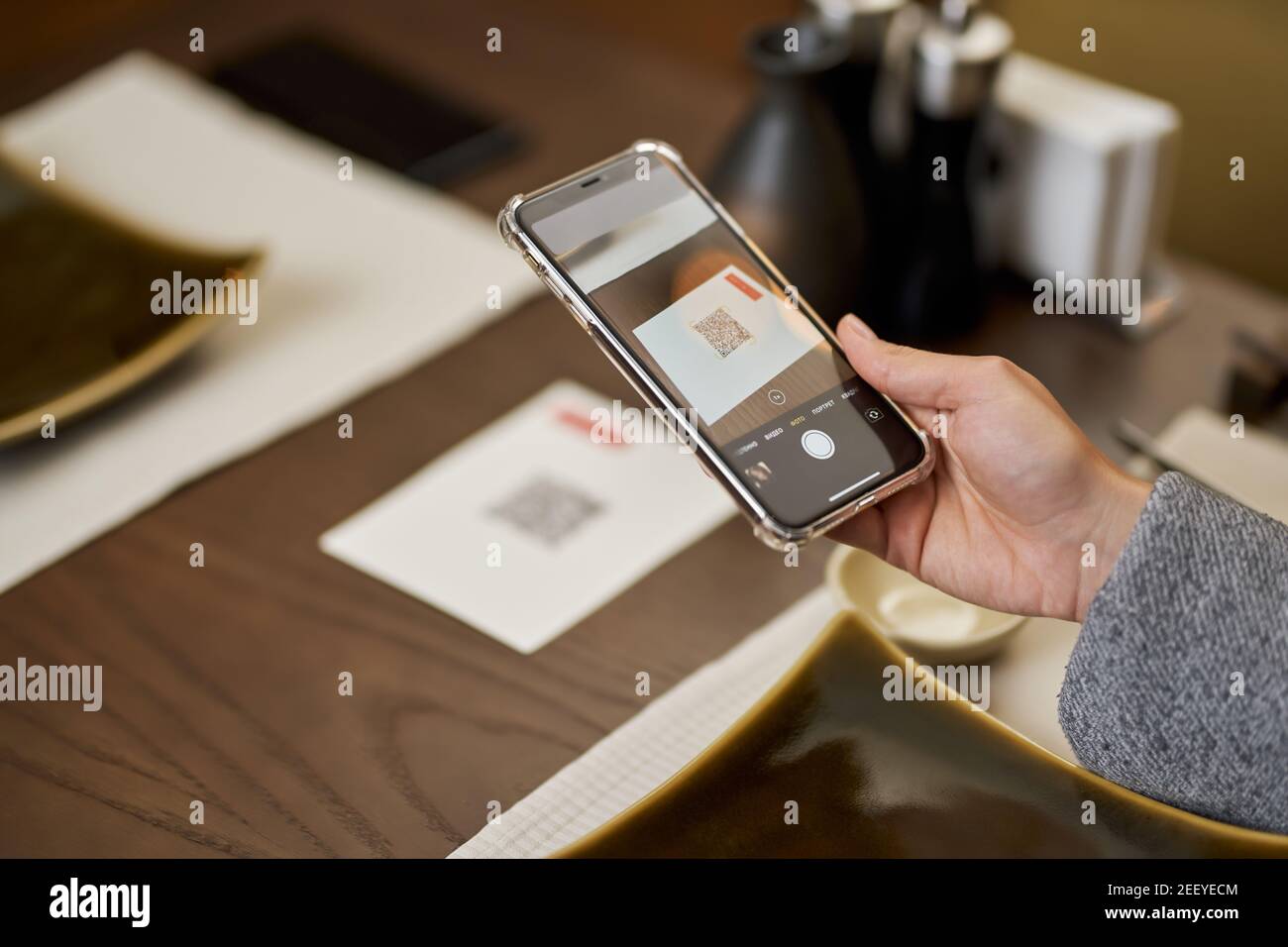 Foto ritagliata della persona che utilizza lo smartphone per la scansione di un codice QR di un menù di caffè Foto Stock