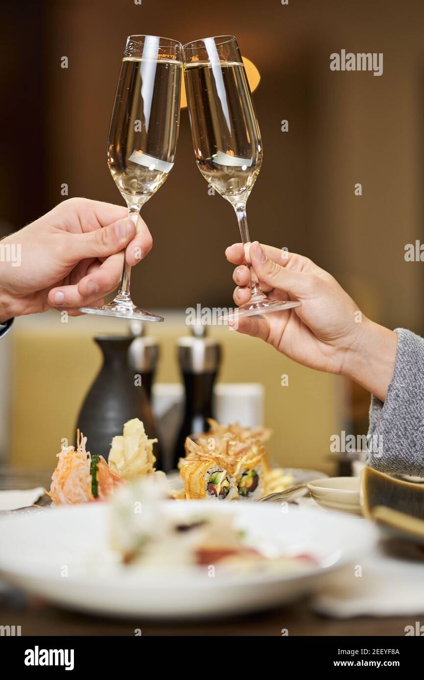 Foto ritagliata di mani che tengono eleganti bicchieri con champagne e. aggraffarli Foto Stock