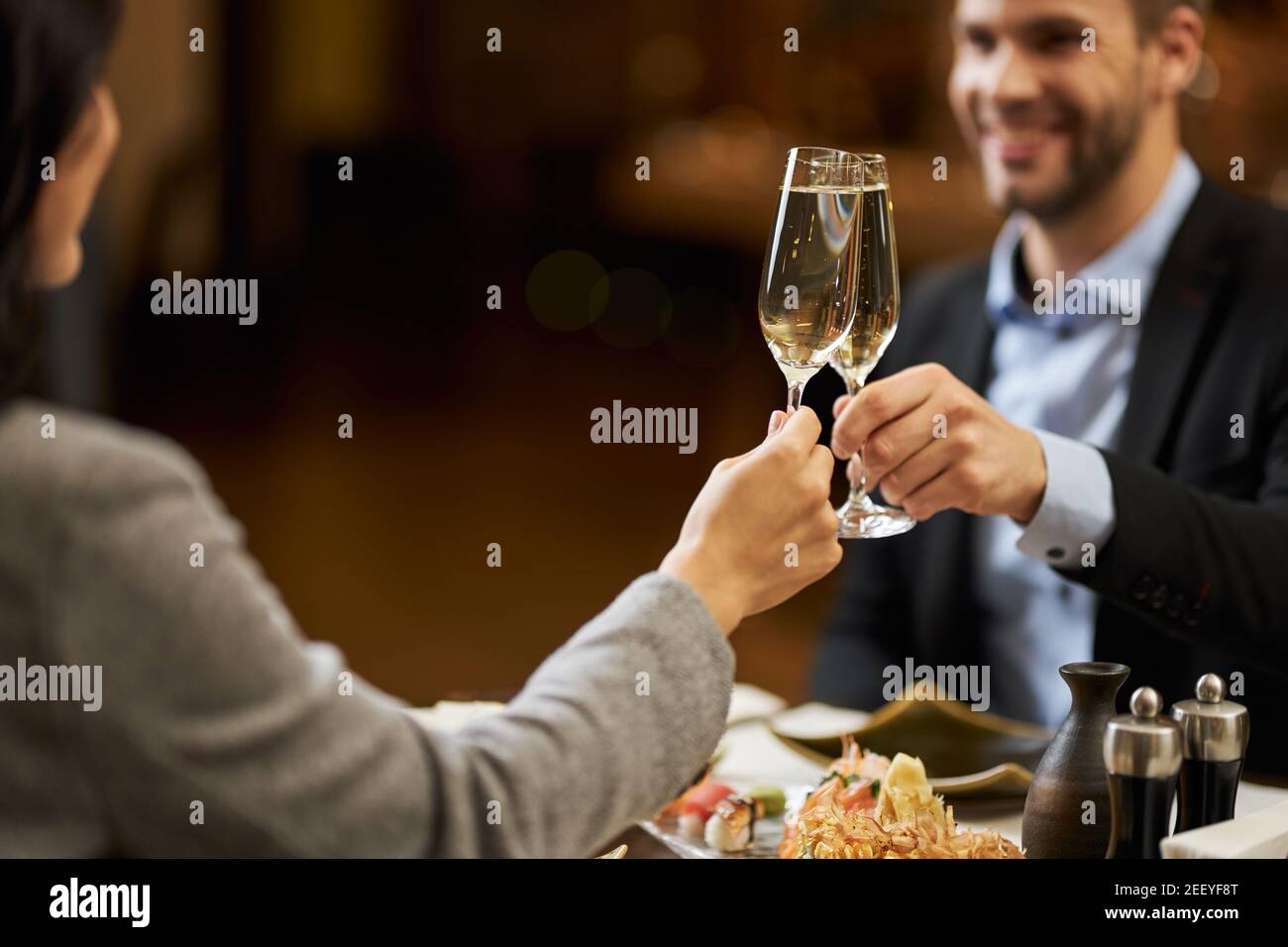 Copia foto spazio di bello uomo e il suo coniuge che si aggrappano i loro bicchieri di champagne mentre cenano in un bel ristorante Foto Stock