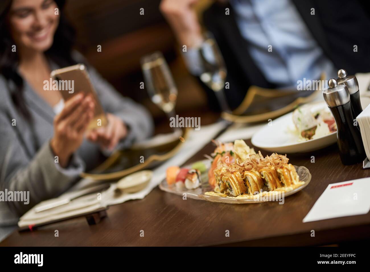 Foto a fuoco selettivo di un piatto di sushi ben preparato con sfocato cafe visitatori sullo sfondo Foto Stock