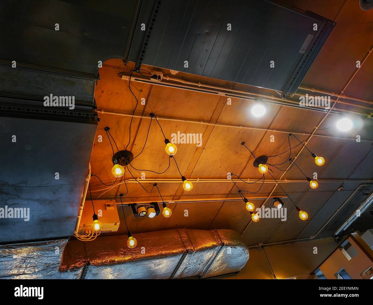 Soffitto con tubi di ventilazione e lampade arancioni decorative Foto Stock