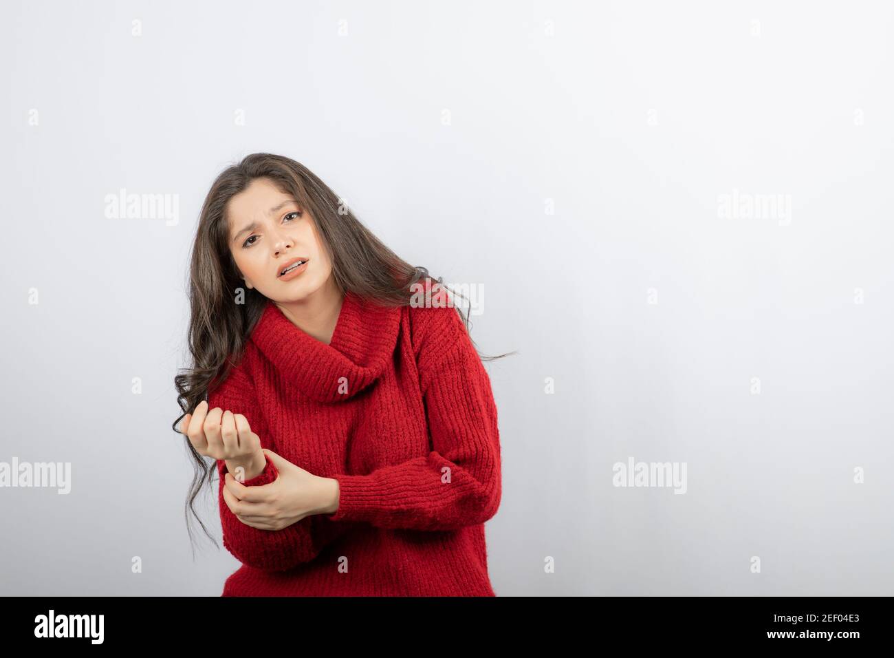 Giovane donna in caldo maglione rosso che soffre di dolore in braccio Foto Stock