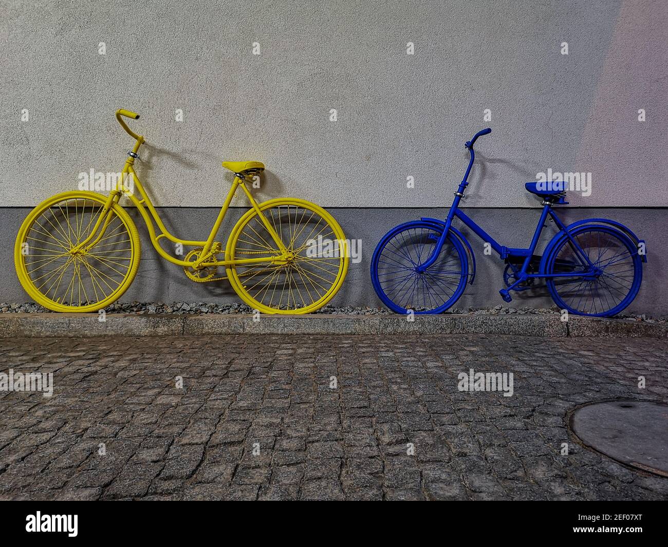 La bici gialla e blu si appoggiò contro il muro Foto Stock