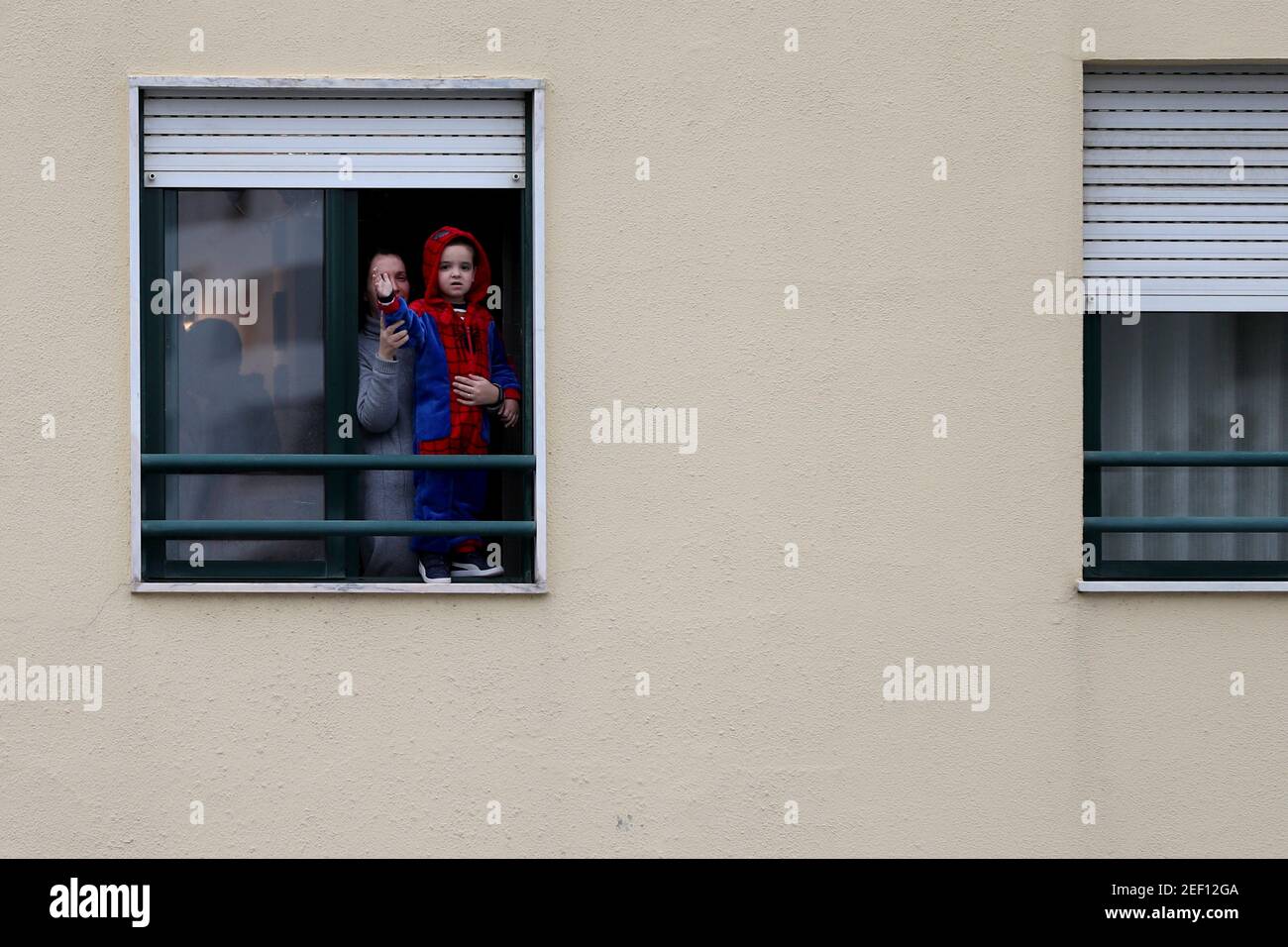 Lisbona, Portogallo. 16 Feb 2021. I festaioli celebrano il Carnevale alle loro finestre, mentre un'auto che suona musica si aggira per le strade di Loures, alla periferia di Lisbona, in Portogallo, il 16 febbraio 2021. Le parate e i festeggiamenti del carnevale portoghese dovevano essere annullati come parte delle misure di blocco in corso contro la pandemia COVID-19, ma alcuni comuni hanno adattato e chiesto ai rivelatori di fare festa nelle loro finestre o online. Credit: Pedro Feuza/ZUMA Wire/Alamy Live News Foto Stock