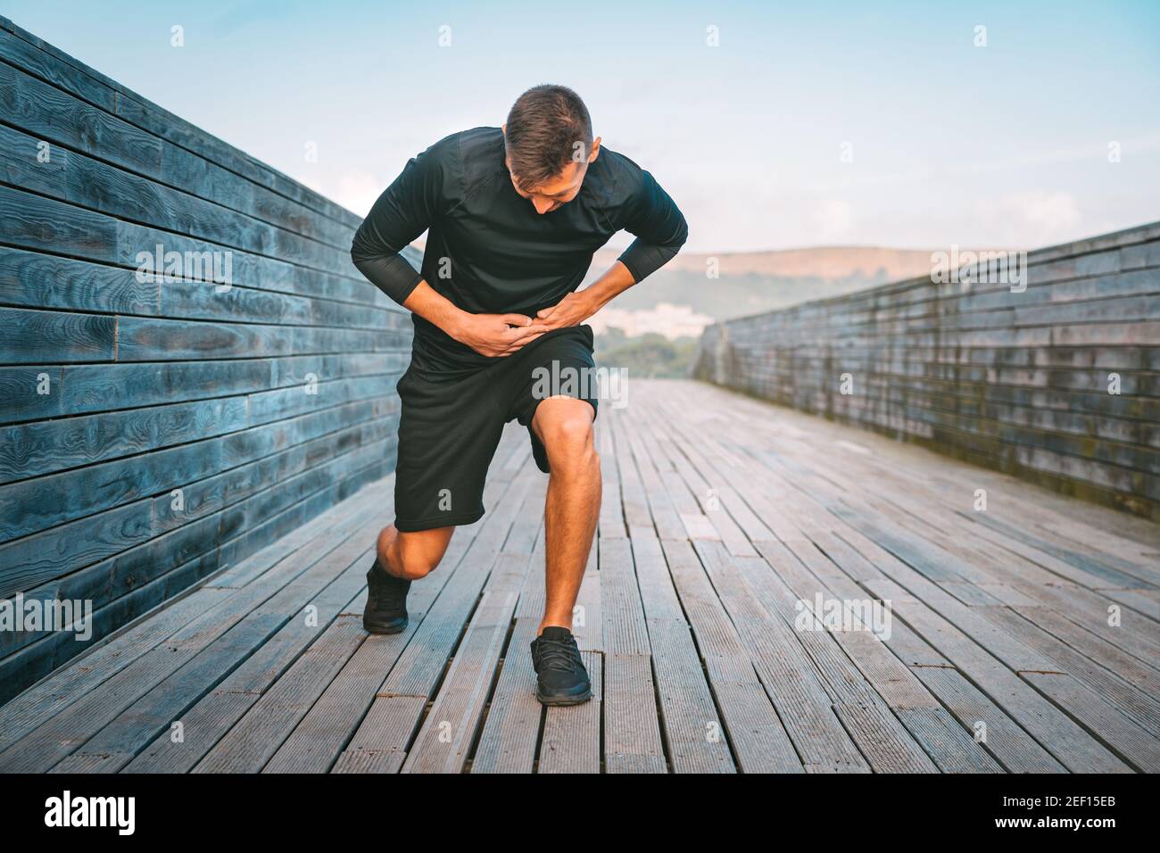 Man Runner con crampi laterali allo stomaco o cuciture durante l'allenamento. Atleta che soffre di dolore al suo fianco. Dolore laterale dopo jogging o corsa. Foto Stock