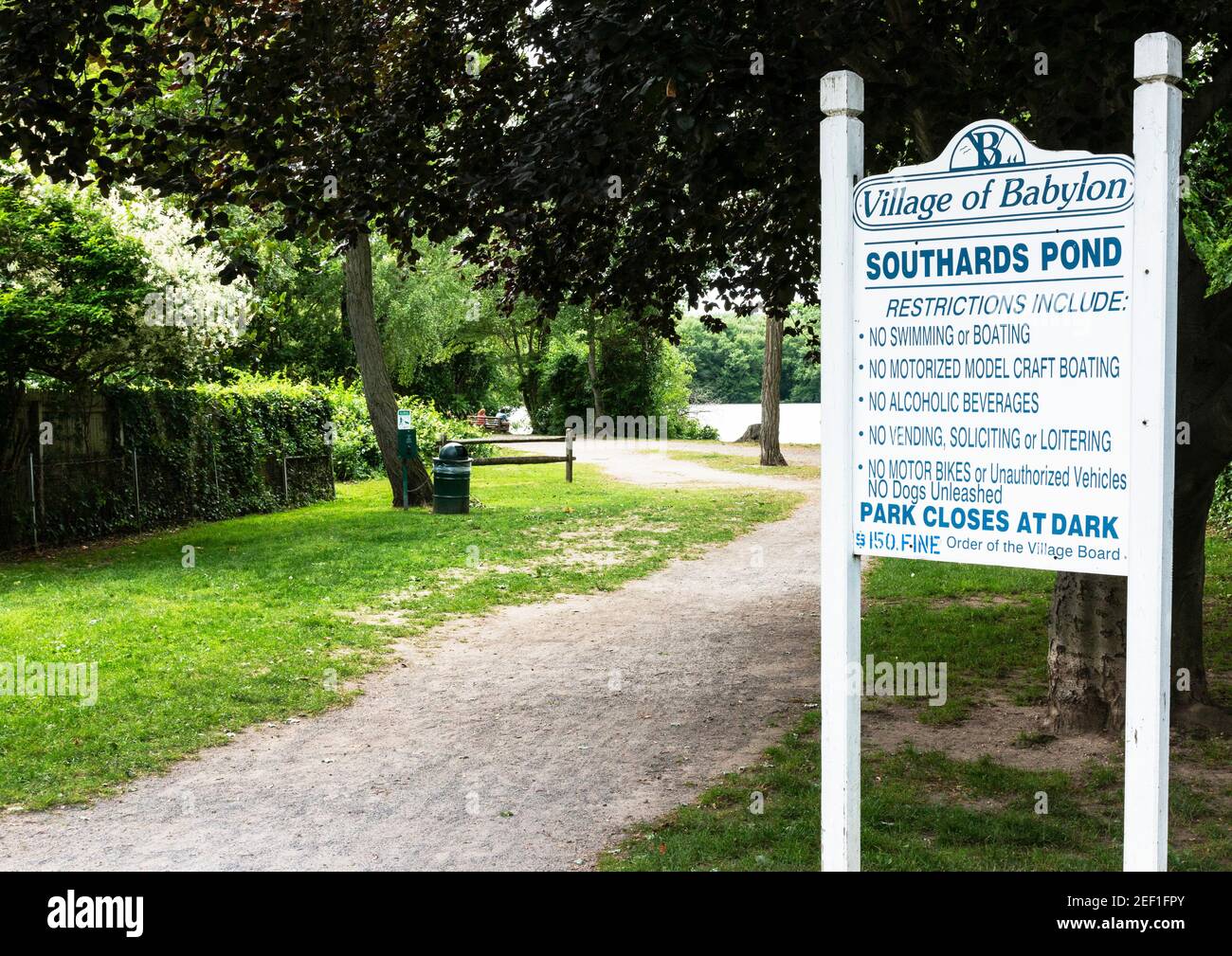 Babylon, New York, USA - 15 Giugno 2018: Guardando l'ingresso di Southards Pond con Babylon Villeges regole per il lago postato su un cartello. Foto Stock