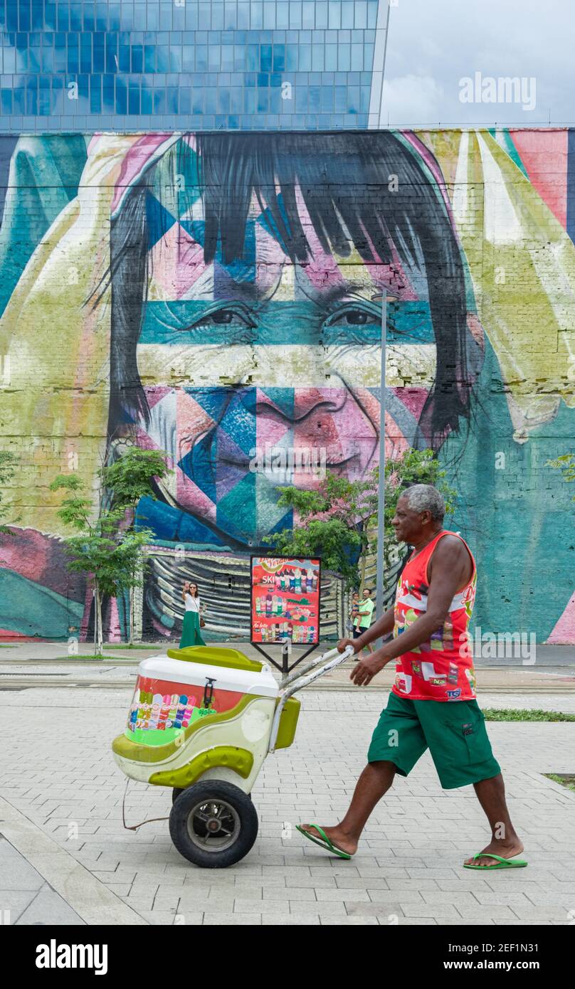 RIO DE JANEIRO, BRASILE - 3 GENNAIO 2020: Un peddler gelato cammina sul Boulevard Olimpico, nella zona portuale di Rio de Janeiro con calle murale d'arte Foto Stock