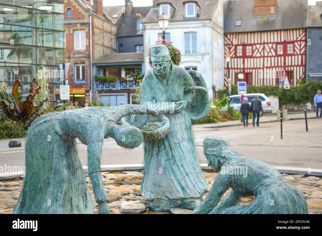 La cozza raccoglitori statua, Les moulieres d'honfleur nel medievale borgo di pescatori di Honfleur Francia con metà case con travi di legno dietro Foto Stock