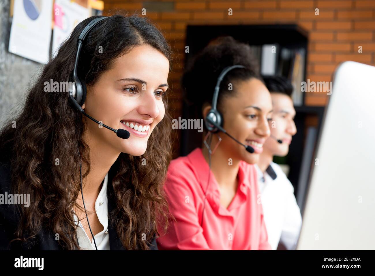 Donna d'affari sorridente che lavora nel call center con il suo team multietnico Foto Stock