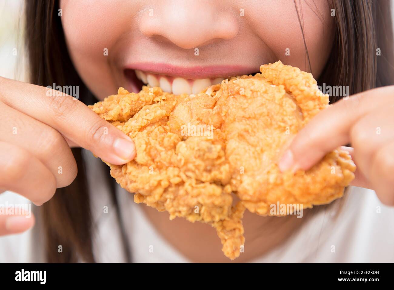 Giovane donna che mangia pollo fritto profondo - primo piano colpo Foto Stock