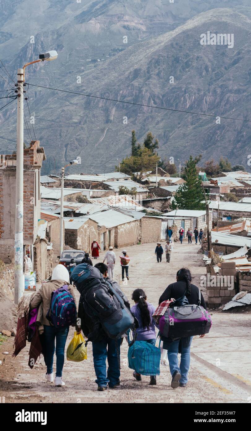 PINCHOLLO, VALLE DEL COLCA, PERÙ - 20 GENNAIO 2018: Una passeggiata peruviana famiglia con borse attraverso la strada con la montagna sullo sfondo nel piccolo vello Foto Stock