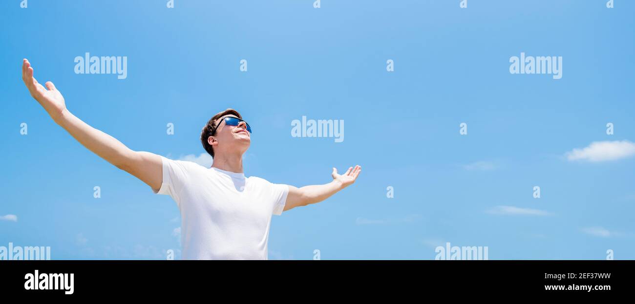 Giovane uomo alzando le braccia, aprendo le palme, guardando in aria che dà potere a se stesso Foto Stock