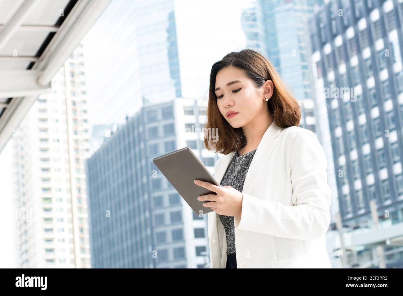 Donna d'affari asiatica che usa un computer tablet con edifici in ufficio sfondo Foto Stock