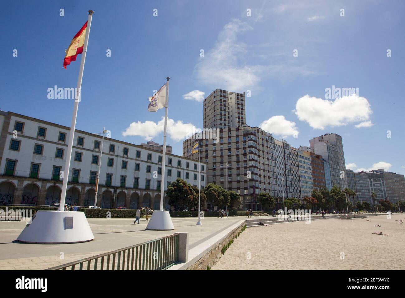 Coruna-Spagna. Bandiere della Spagna e della Galizia che sventolano nel vento sulla passeggiata con la spiaggia di Riazor e gli edifici sullo sfondo il 3 giugno 2017 Foto Stock