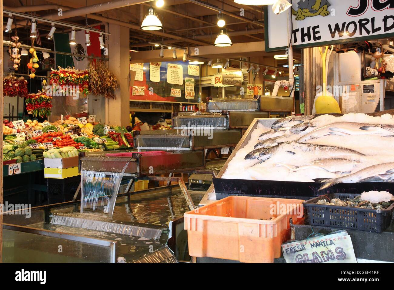 Verdure e pesce in vendita nelle alte bancarelle del Pike Place Market. Questo mercato agricolo è una vista famosa nel centro di Seattle. Foto Stock