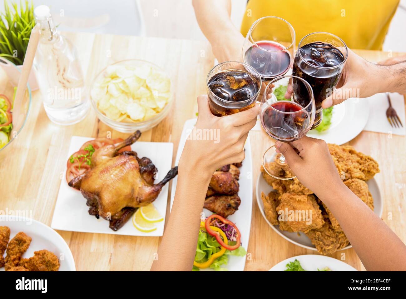 Gruppo di amici che si accovacciano bicchieri, grazie, al tavolo da pranzo nella festa Foto Stock