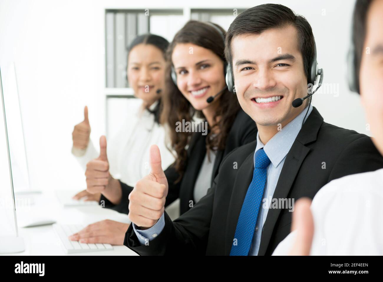 Sorridente team di assistenza clienti che dà il pollice in su nel call center Foto Stock