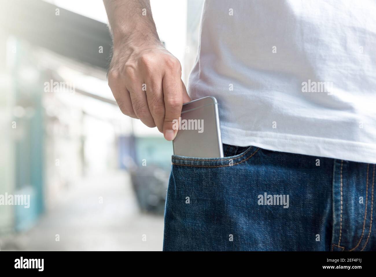 Un uomo che raccoglie smartphone dalla tasca dei jeans Foto Stock