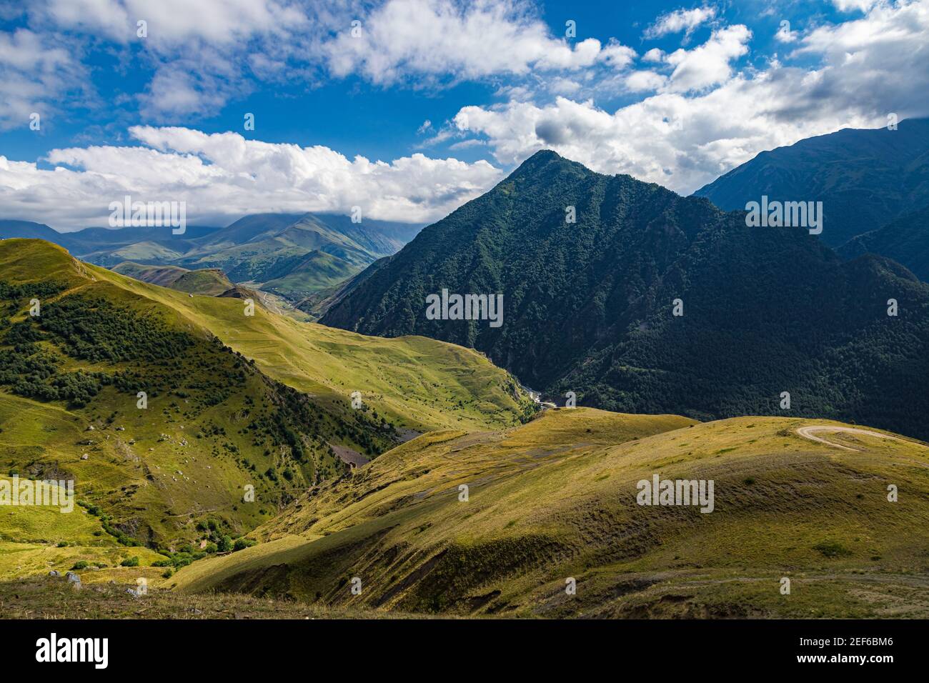 Alte montagne del Caucaso con splendide viste. Vegetazione verde e fitta foresta sopra un cielo blu. Un grande paesaggio affascinante. Foto Stock