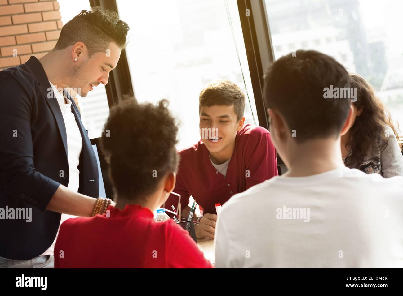 Giovani occasionali uomini d'affari multietnici che prestano attenzione al loro amico nella discussione di gruppo (riunione) Foto Stock