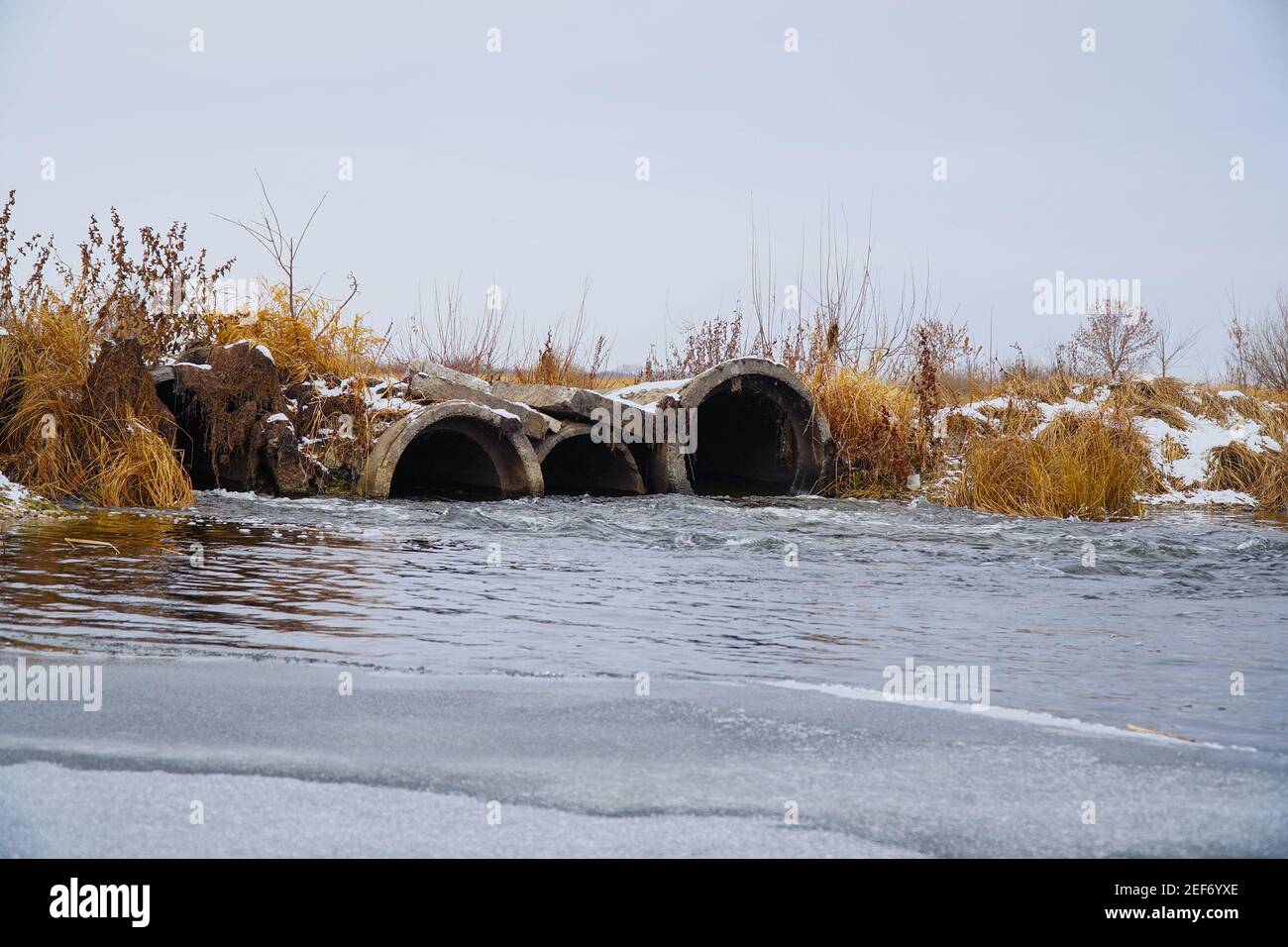 L'acqua sul fiume scorre da grandi tubi. Diga sul fiume Foto Stock
