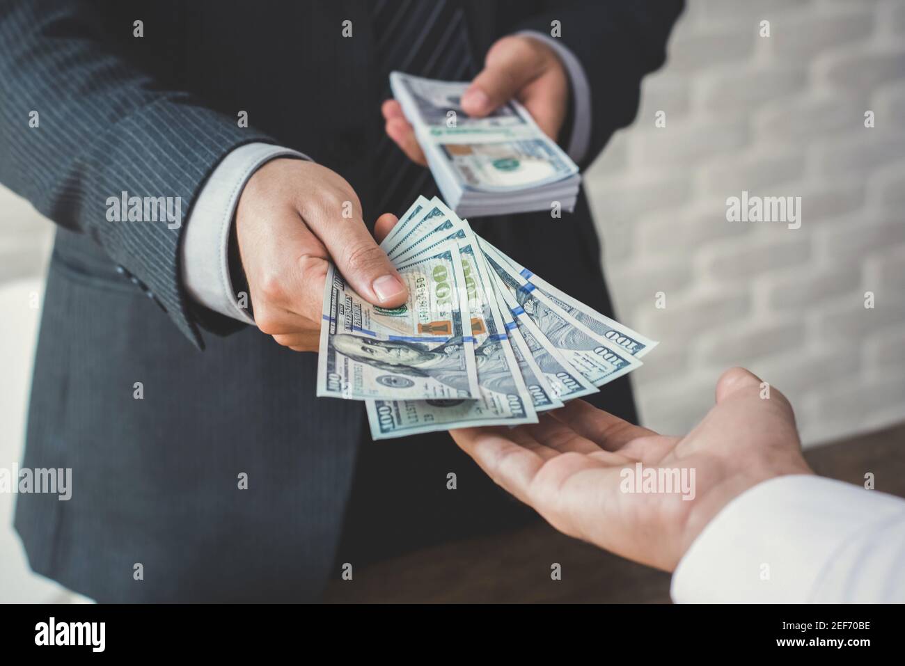 Uomo d'affari che dà o paga i soldi ad un uomo, le fatture del dollaro degli Stati Uniti - prestito, corruzione e concetti finanziari Foto Stock