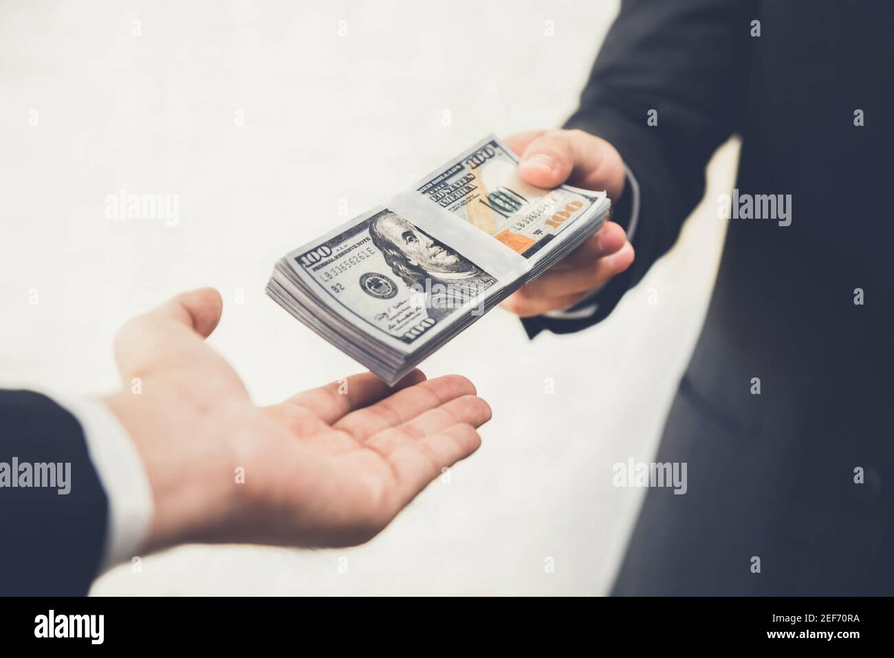 Uomo d'affari che dà (o che paga) i soldi ad un uomo, le fatture del dollaro degli Stati Uniti - concussione, prestito e concetti finanziari Foto Stock