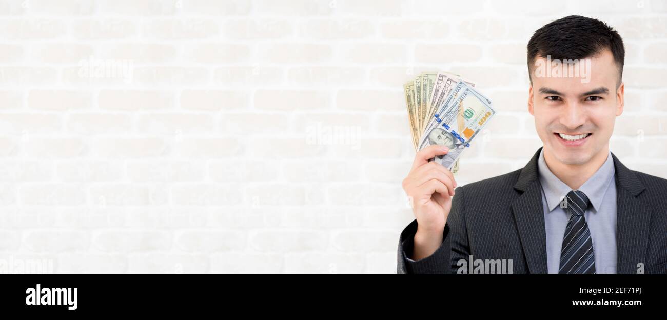 Giovane uomo d'affari sorridente che mostra i soldi del dollaro degli Stati Uniti, bandiera con lo spazio di copia Foto Stock